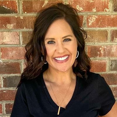 Samantha Hudeck smiling and standing in front of a brick wall