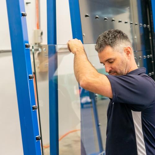 worker in front of glass coating machine